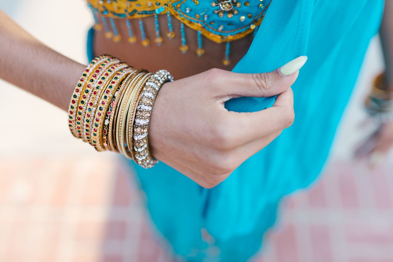 Close-up of colorful bangles on a womans hand wearing traditional blue attire, showcasing Indian culture.