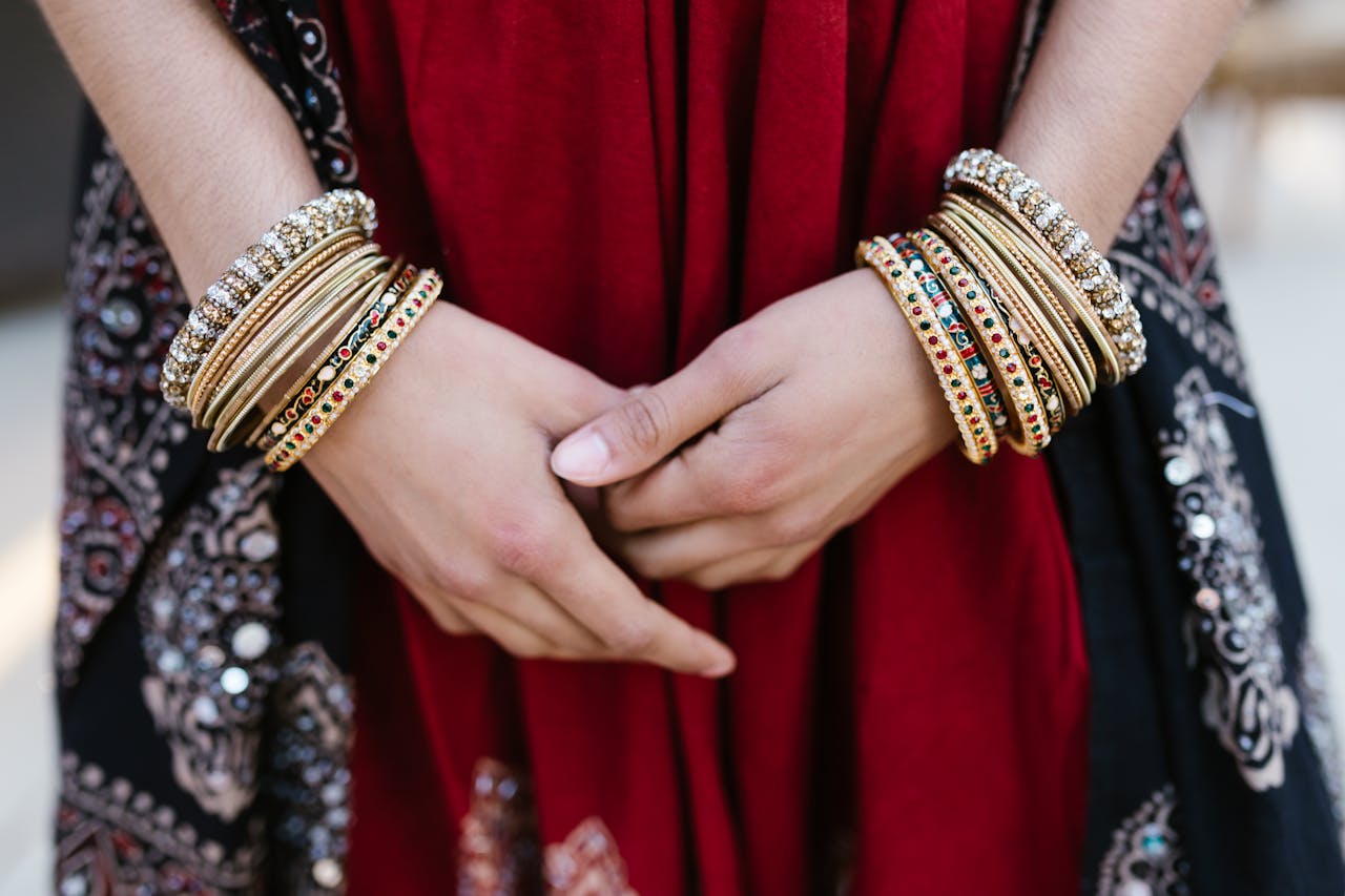 Close-up of a womans hands adorned with colorful traditional bangles, showcasing cultural attire.