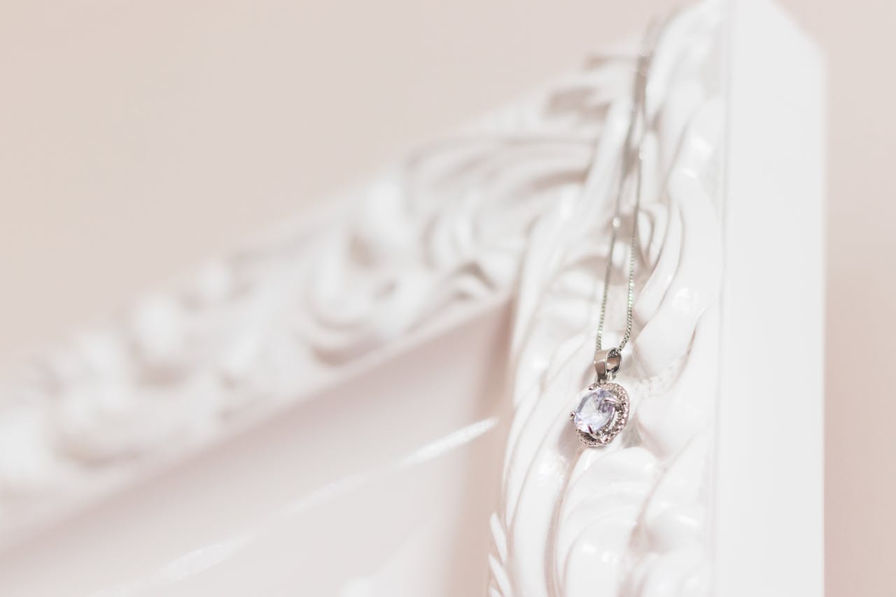 Close-up of a silver pendant necklace hanging on an ornate white frame. Perfect for jewelry and fashion themes.